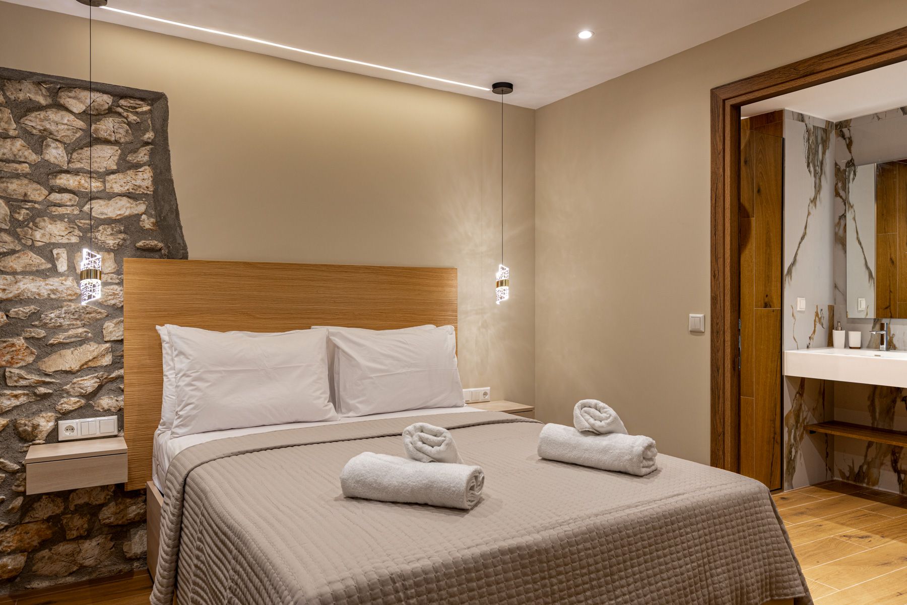 The bedroom in Anemoessa, framed by bare stone beside the bed