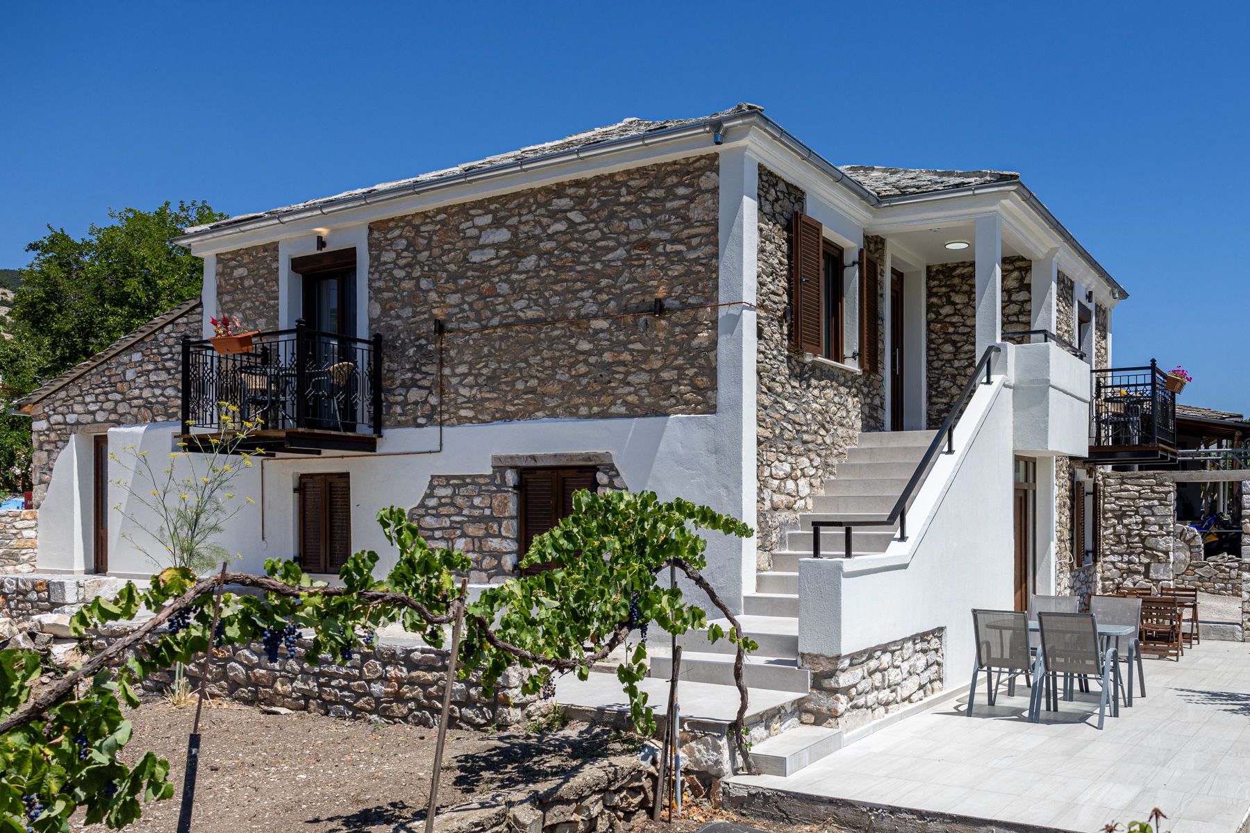 The stone house seen from the vineyard, with the hills of Thassos behind